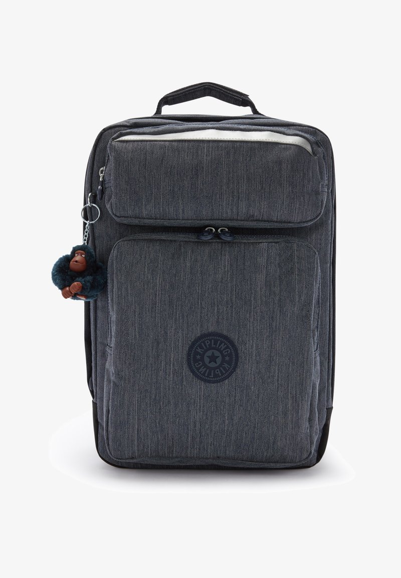 Szary plecak z materiału, posiadający liczne zapinane na suwak przegródki, okrągłą naszywkę z logo oraz futrzany breloczek w kształcie małpki.