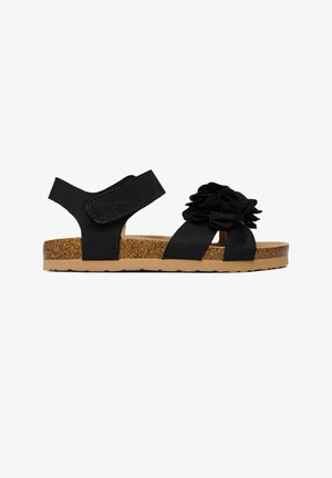 Sandale negre cu talpă de plută, bretea reglabilă pentru gleznă și detaliu mare cu floare din material textil peste bretelele din față.