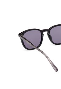 Ochelari de soare negru cu lentile de un violet închis. Cadru din plastic elegant, accente metalice și brațe drepte cu o textură subtilă în degrade.