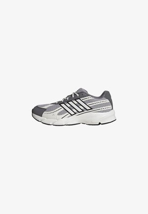 Grauer und weißer Sportschuh mit Mesh-Einsätzen, schwarzen Streifen und weißer Sohle, von der Seite auf weißem Hintergrund gezeigt.