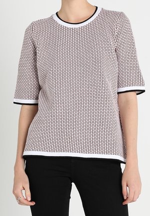 Top de manga corta con un diseño de malla que presenta un patrón rojo y blanco. Cuello redondo acanalado y detalles en negro en las mangas y el dobladillo.