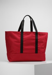 Borsa a tote in tessuto rosso con manici neri, forma rettangolare e design strutturato. Presenta una texture liscia e nessun motivo visibile.