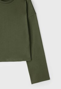 Olivgrünes, langärmliges, kurzes Shirt mit rundem Halsausschnitt und lockerem Schnitt, vor weißem Hintergrund dargestellt.