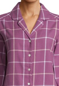 Paars geruit shirt met een lichtpaarse en witte ruitpatroon. Bevat een gekantelde kraag en zilveren knopen aan de voorkant.