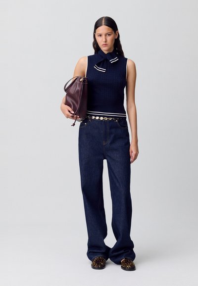 Top sin mangas de punto en color azul marino con cuello de lazo, acompañado de unos vaqueros de pierna ancha de talle alto en azul oscuro y un bolso marrón. Sandalias con estampado de leopardo.