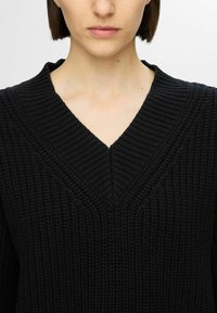Maglione nero a maglia con scollo a V, texture a coste e distintivi motivi verticali nel tessuto.