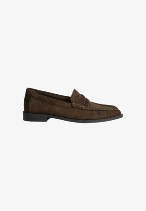 Mocasines de ante marrón con punta redondeada, costura decorativa en la parte superior y un bajo tacón de goma negra. Textura lisa y diseño clásico.