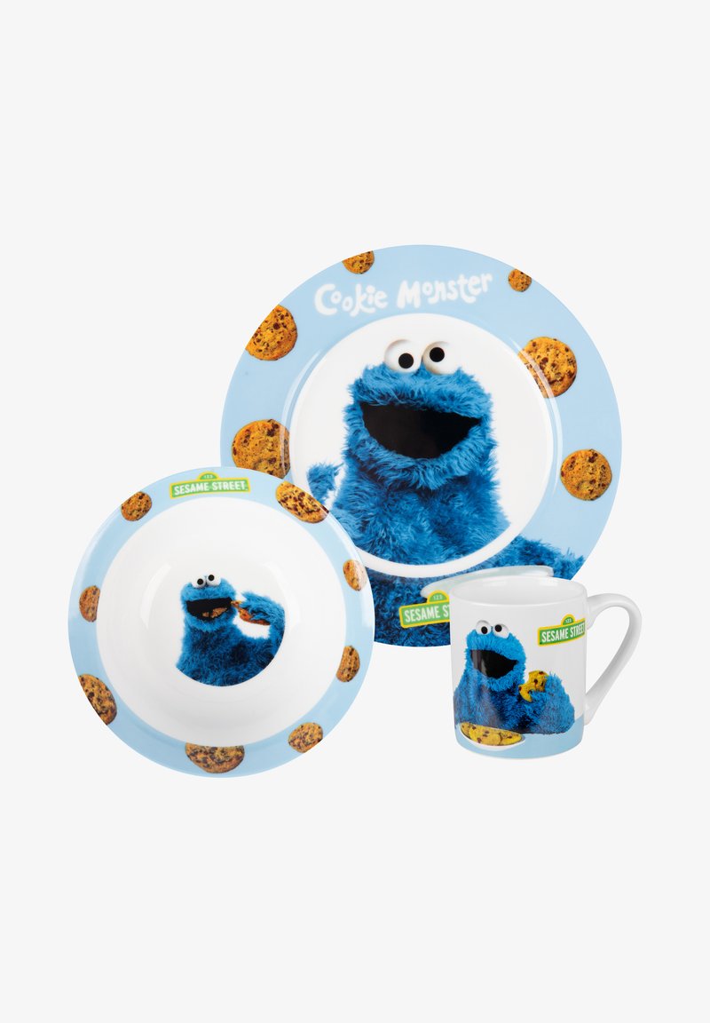 Ceramic dishware set featuring Cookie Monster. Blue color, fuzzy texture graphic. Includes a plate, bowl, and mug with cookie patterns.
