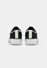 Μαύρα καμβά sneakers με λευκή ρίγα, υφασμάτινη σόλα και ανάγλυφο λογότυπ�ο στη φτέρνα. Στρογγυλή σιλουέτα με σχέδιο χαμηλού κόψιμου.