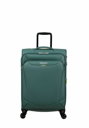 Valigia rigida di colore teal, con una superficie liscia, manico retrattile, quattro ruote e chiusura a zip. Logo visibile sul davanti.