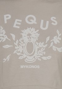 Šviesiai smėlinis džemperis su reljefu išspausdintu balta tekstu "PEQUUS" ir gėlių dizainu, kurio centre yra dekoratyvinis elementas. Po juo spauda "MYKONOS".