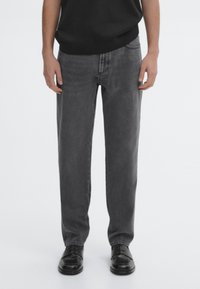 Gray denim jeans with a straight leg cut, featuring five pockets and a classic waistband. Paired with black leather shoes.