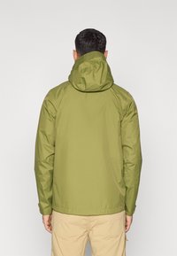 Χακί πράσινο μπουφάν με κουκούλα, κατασκευασμένο από λείο, αδιάβροχο ύφασμα. Διαθέτει ραγκλάν μανίκια και ίσια γραμμή.