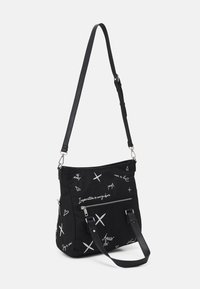 Schwarze Stofftasche mit einem lässigen Design, ausgestattet mit einem Muster aus weißem Text und Symbolen, einem verstellbaren Träger und einer Reißverschluss-Fronttasche.