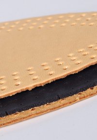 Tan leather insole with perforated texture on the top, black rubber layer below, featuring smooth edges and a layered design.
