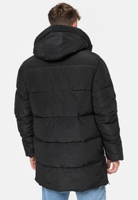 Abrigo tipo puffer negro con capucha, con diseño acolchado y puños elásticos. De longitud media, textura suave y bolsillos con cremallera.