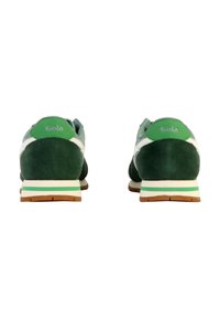 Zapatillas de running de ante verde con acentos blancos, suela plana con detalles a rayas, logo en el talón, punta redondeada y textura suave.