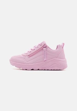 Pink chunky sneaker med snørebånd foran, sidelukning med lynlås, brandet trækflig og tyk mønstret sål på ensfarvet baggrund.