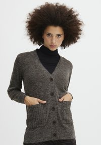 Cardigan in maglia marrone con scollo a V, chiusura a bottoni e due tasche frontali. Maniche e orlo a costine aggiungono texture al design complessivo.