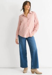 Button-up shirt with pink and white vertical stripes, paired with wide-leg blue denim jeans and beige heeled ankle boots.