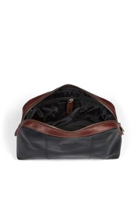 Svart läderväska med bruna läderaccenter. Har en dragkedja upptill, rymligt inre, innerfack och en mjuk yta.