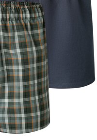 Geruite short in groen, wit en oranje, met een elastische tailleband; gecombineerd met een effen donkerblauwe shirt met een gladde textuur.