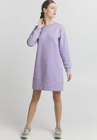 Laventelinen college-mekko, jossa on pitkät hihat, pyöreä kaula-aukko ja ribbireunus. Yhdistetty beigeihin ja harmaisiin lenkkareihin rennon ilmeen saavuttamiseksi.