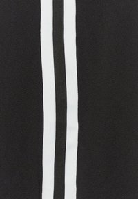 Czarna tkanina o teksturowanej powierzchni ma dwa wyraźne pionowe paski: jeden biały i jeden czarny.