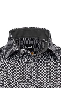 Camicia a righe bianco e nero con un design geometrico, chiusura a bottoni e una fodera del colletto grigia a contrasto. Etichetta della taglia visibile.