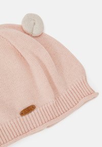 Gorro de malha rosa com um design texturizado, um pompom creme no topo e uma pequena etiqueta de logotipo castanho na base.