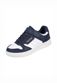Zapatilla navy y blanca con parte superior de cuero, detalles perforados, cordones en la parte delantera y una correa de Velcro. Suela de goma para agarre y soporte.