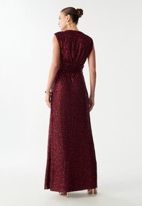 Burgundia sädelev õhtukleit, millel on voolujoondeline siluett, varrukateta disain, r gathered vöökoht ja maani äär.