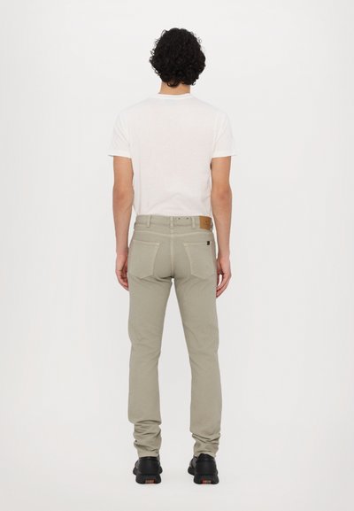Khaki värvi slim-fit püksid, mis on valmistatud puuvillasegistusest, kahe tagataskuga ja nahkse sildiga. Kombineeritud klassikalise valge T-särgi ja mustade kingadega.