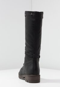 Sort læder støvle i knæhøjde med en glat tekstur, der har en dekorativ remdetalje og en lav brun sål. Metalaccent nær toppen.