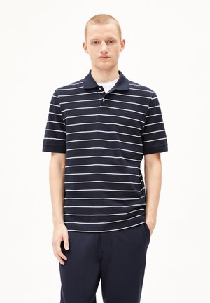 Polo shirt marine à rayures blanches horizontales, à manches courtes, avec un col et deux boutons. Texture lisse, design simple, coupe ajustée.