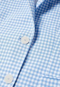 Tessuto della camicia a fantasia vichy in blu chiaro e bianco, con colletto pieghevole, dotato di bottoni in plastica bianchi e una singola tasca sul petto.