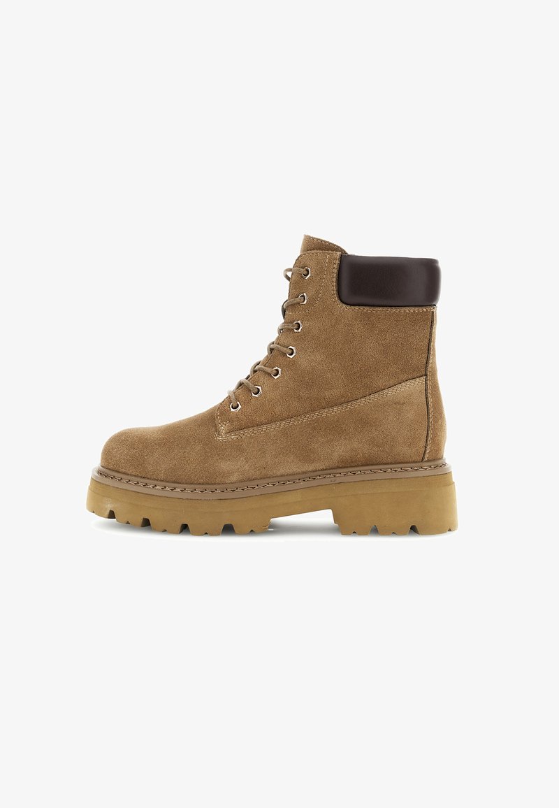 Bota de tobillo de ante marrón con un acento de cuero marrón oscuro en el puño, que presenta ojales de metal y una suela de goma rugosa y con diseño.
