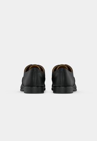Pair of black leather dress shoes viewed from the back on a plain white background.