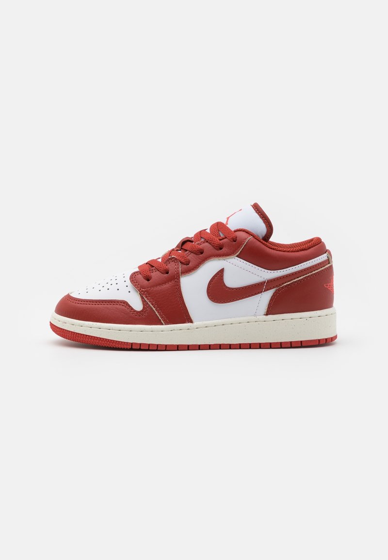 Baskets basses avec des panneaux en cuir rouges et blancs, des lacets rouges et un swoosh Nike rouge sur le côté, présentées sur fond blanc.