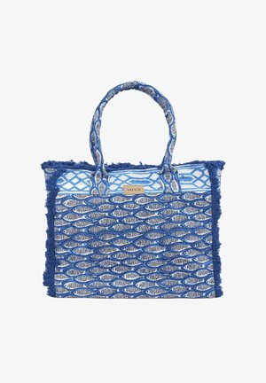 Borsa tote intrecciata blu e bianca con motivi geometrici e a scaglie di pesce, manici in tessuto e bordi sfrangiati, con una piccola etichetta "Verde".