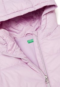 Světle fialová péřová bunda s kapucí, která má hladký vnější povrch, fleecovou podšívku a zapínání na zip. Viditelný zelený štítkový logo značky.