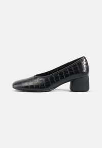 Cizme din piele cu textură în relief de crocodil, de culoare neagră, cu vârf rotund, toc mic și textură netedă. Design simplu și siluetă minimalistă.