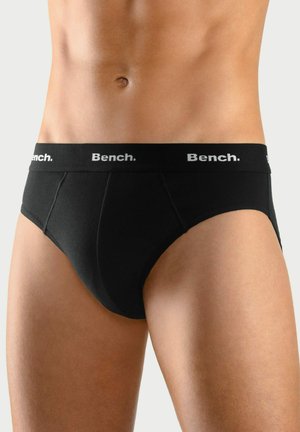 Caleçons en coton noir avec une large ceinture élastique comportant le nom de la marque "Bench." L'avant présente une texture lisse et une forme ergonomique.