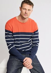 T-shirt à manches longues avec une partie supérieure orange et une partie inférieure à rayures bleu marine. Fabriqué en coton avec une texture douce. Conception à encolure ronde avec des rayures blanches.