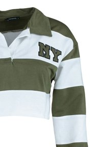 Polo de rayas verdes y blancas, cortado, con cuello y "NY" bordado en verde oscuro en el lado izquierdo del pecho. Tacto de tela suave.