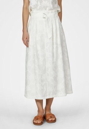 Weißer Midirock mit dezentem Blumenmuster und Gürtel, getragen mit hellbraunen offenen Slip-On-Sandalen.