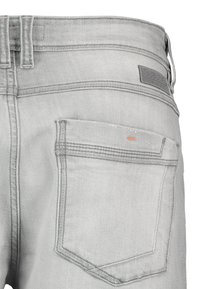 Helle graue Denim-Jeans mit gestickten Taschen und einem Leder-Logo-Patch am Bund. Sie verfügen über eine glatte Textur und ein strapazierfähiges Material.