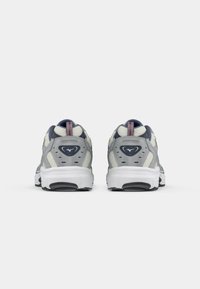 Gray and white athletic shoes with a textured mesh upper, supportive heel counter, and visible branding on the back.