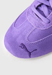 Paarse suède sneaker met een afgeronde neus, een gestructureerd oppervlak en gestikte details. Voorzien van een geborduurd logo aan de zijkant.