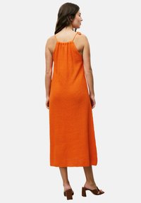 Orange, ärmelloses Maxikleid aus strukturiertem Stoff, gerafftem Rücken und seitlichem Bindedetail. Ergänzt durch braune Blockabsatzsandalen.
